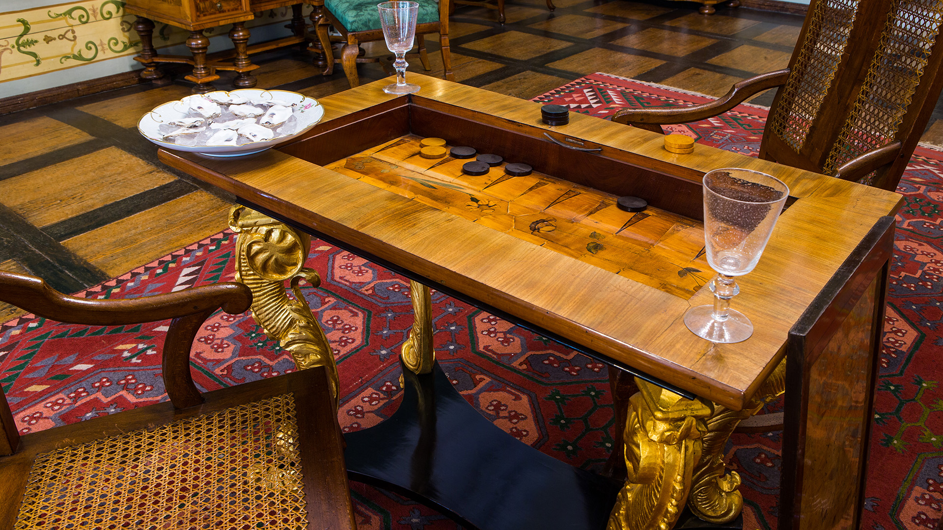 Auf dem Bild zu sehen ist im zweiten Vorzimmer des Herzoginnen-Appartements ein Spieltisch mit einem eingelassenen Backgammon-Spiel. Auf dem Rand stehen links ein Teller mit Austern und auf zwei weiteren Ecken Trinkgläser.