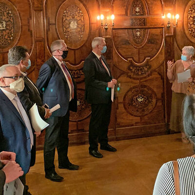 Dr. Donner referiert vor sechs Personen, die ihr zugewandt im Halbkreis vor ihr stehen, im holzverkleideten Intarsienkabinett des Schloss Museums.