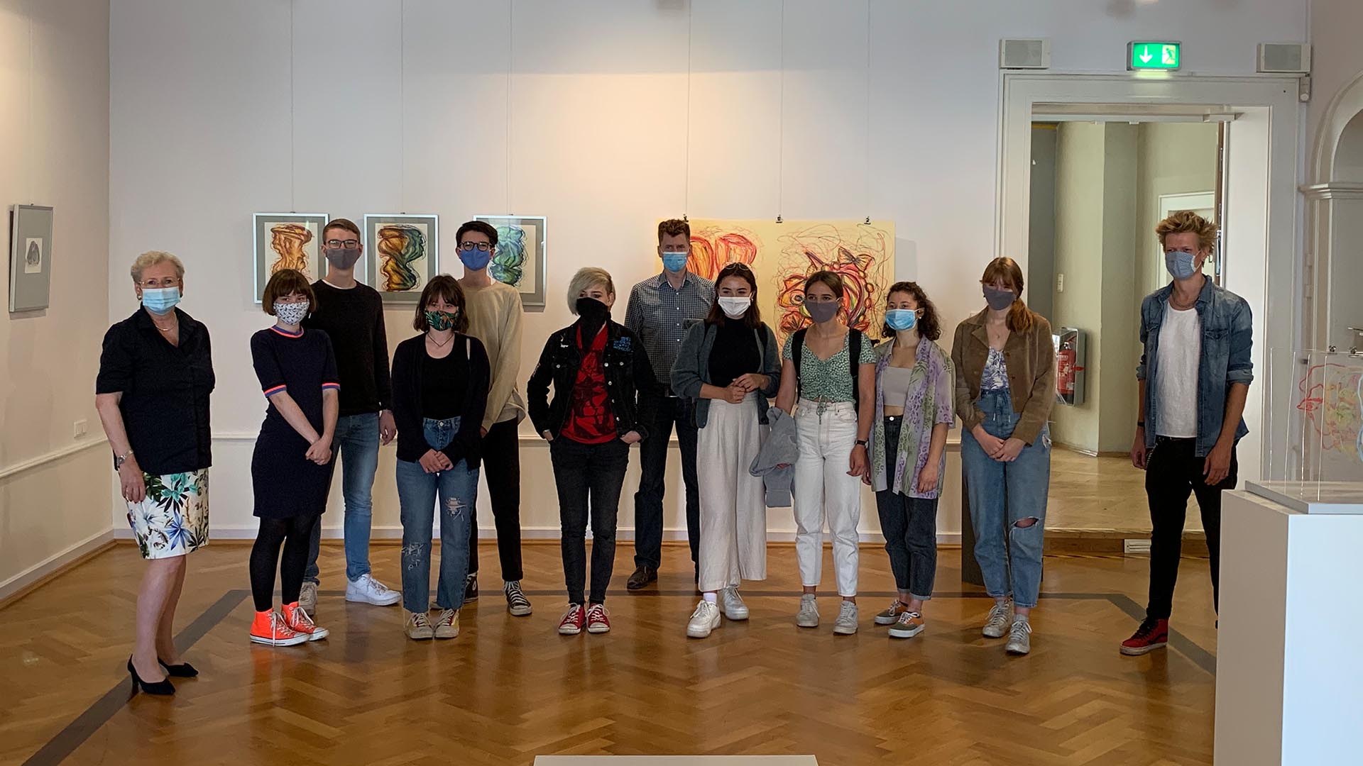 Schülerinnen und Schüler des Gymnasiums im Schloss, die Projektverantwortlichen und Olaf Behn stehen zusammen in der Ausstellung.