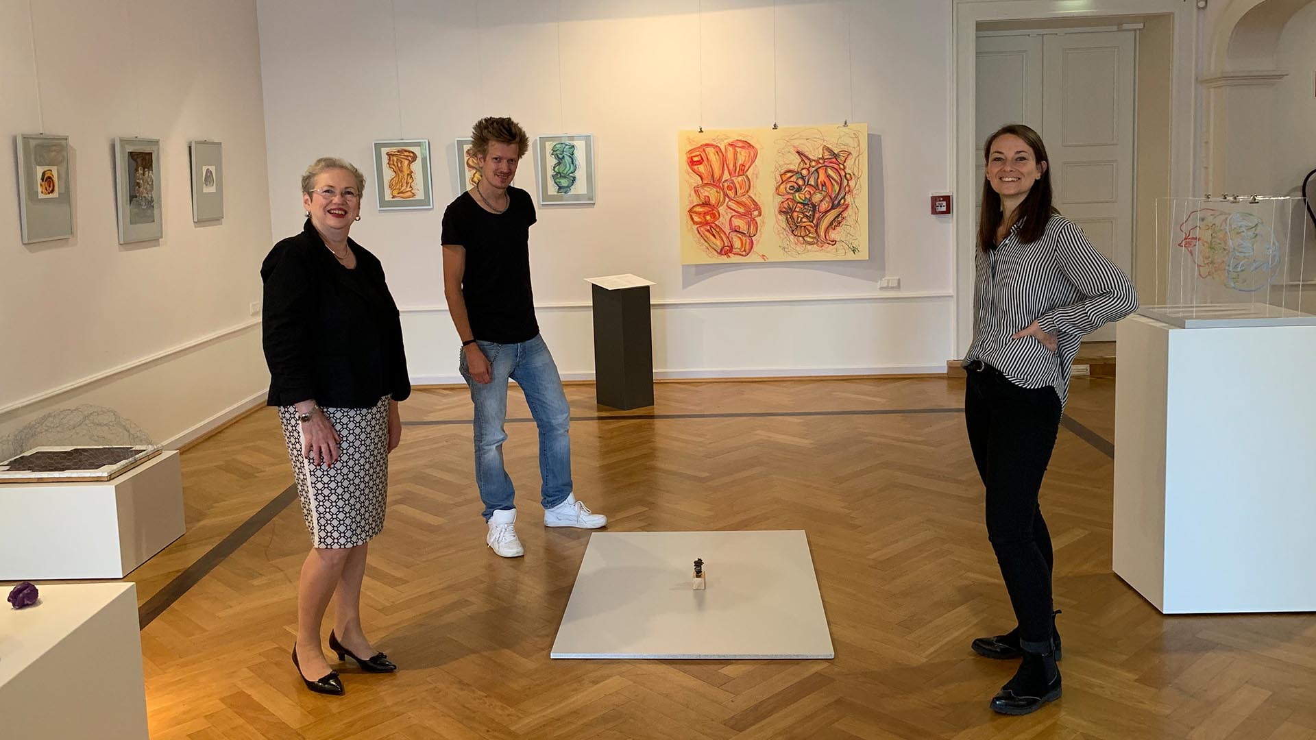 Cortina Teichmann, Sven Bode und Stella Gilfert stehen inmitten der Schülerausstellung im Schloss.
