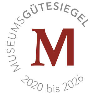 Um eine rotes großes M steht im Kreis "Museumsgütesiegel 2020 bis 2026".