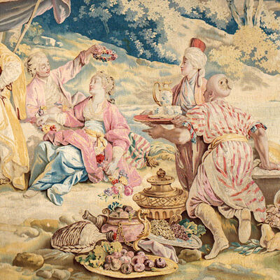 Die Abbildung zeigt einen Wandteppich, auf dem eine höfische Gesellschaft im Grünen dargestellt ist. Die Personen musizieren, essen und rauchen Wasserpfeife. Im Hintergrund stehen Zelte aus teurem Stoff.