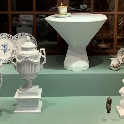 In einer Vitrine steht Porzellan aus der Manufaktur Fürstenberg: Teller, Teile eines Kaffeeservice, eine Vase und Behölter in Amphorenform, eine Skuptur.