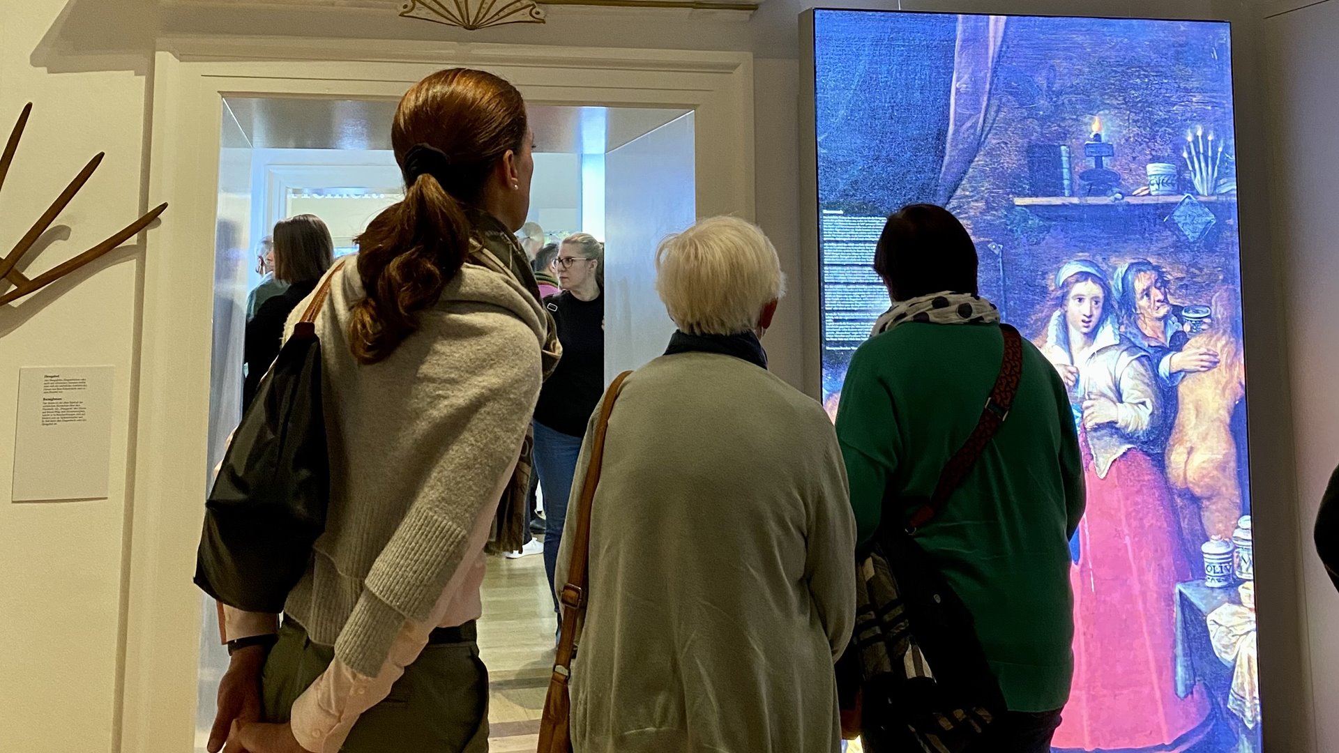 Drei Personen stehen vor einem Bild aus der Ausstellung.
