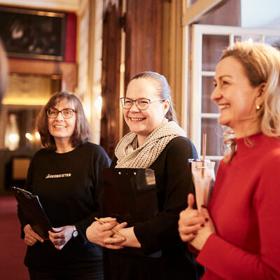 Drei Frauen stehen in einem historischen Raum des Schloss Museums und lächeln